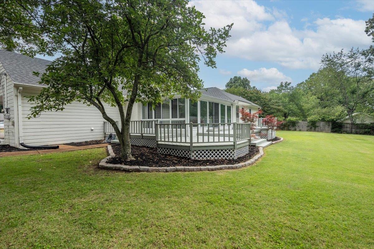 670 Peterson Lake Road Collierville, TN 38017 - Photo 29 of 37 Expansive green lawn featuring a multi-level deck with white railings and lattice skirting, a screened porch, mature tree, and landscaped planting beds