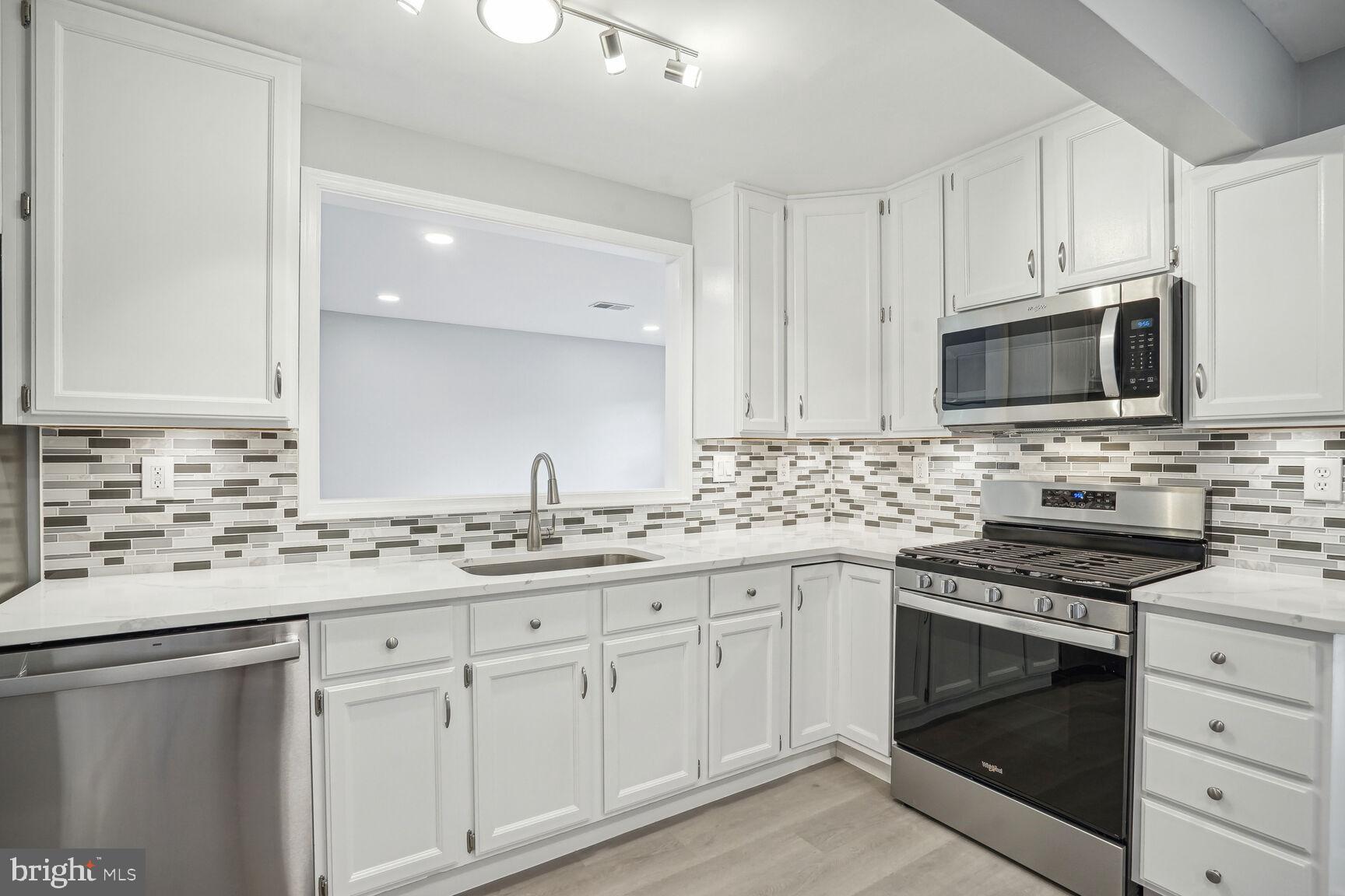 a kitchen with granite countertop white cabinets sink and stainless steel appliances