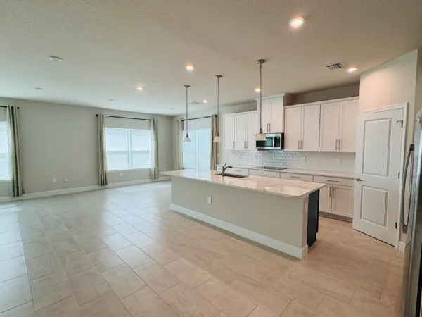a large kitchen with stainless steel appliances kitchen island a large counter top a stove and a refrigerator