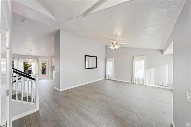 7 Reflection Way St. George, UT 84770 - Photo 5 of 54 Unfurnished living room with light wood finished floors, ceiling fan, stairway, a textured ceiling, and beam ceiling