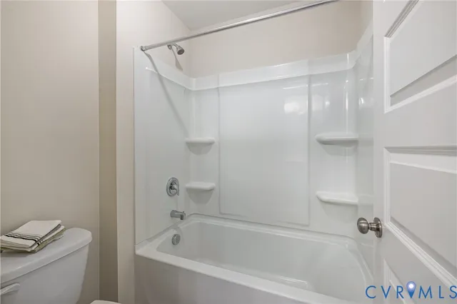 a white bath tub sitting next to a white toilet and vanity