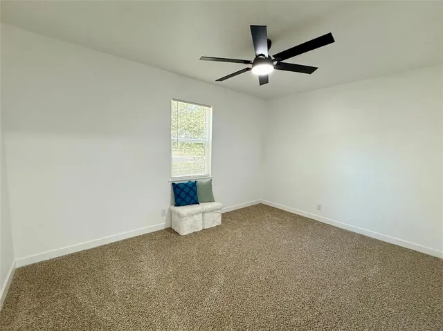 an empty room with a window and a ceiling fan