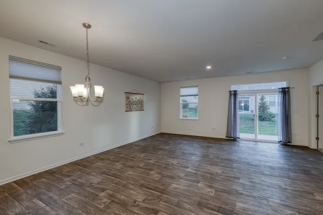 an empty room with wooden floor cabinet and windows