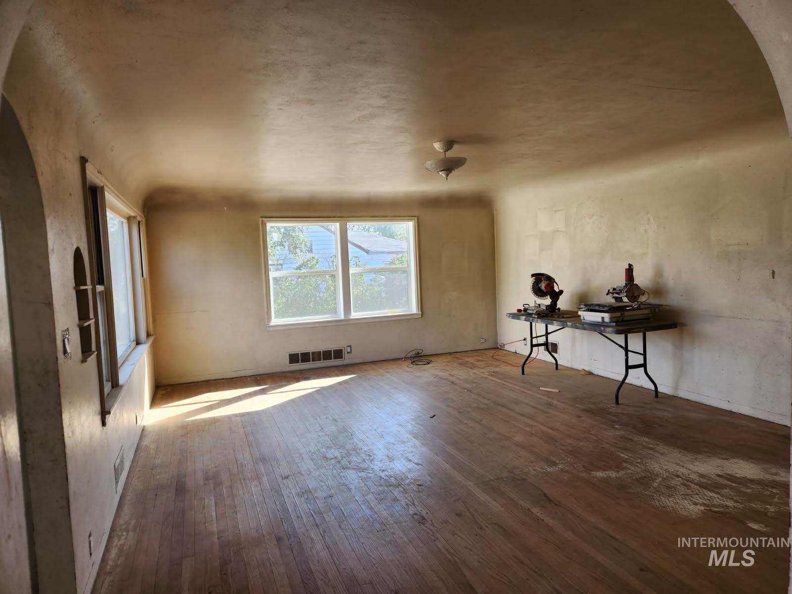 525 North 4th Street Nyssa, OR 97913 - Photo 4 of 17 Unfurnished living room featuring arched walkways and wood-type flooring