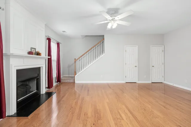 a view of an empty room with wooden floor and a fireplace