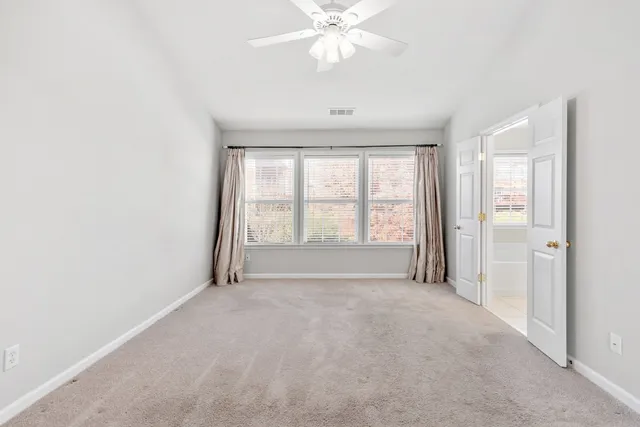 an empty room with windows and chandelier fan