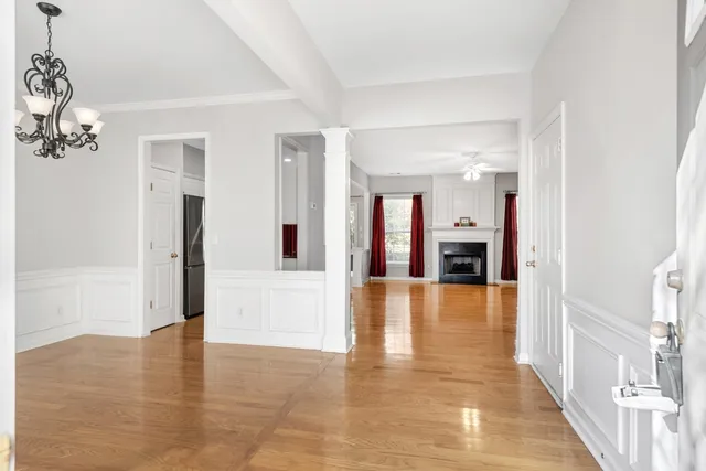 a view of a hallway with wooden floor and a chandelier