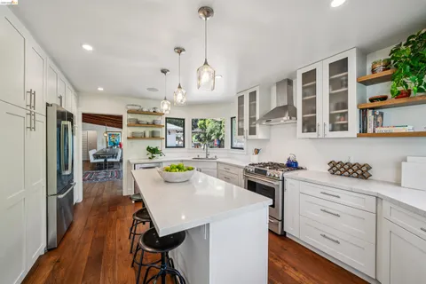a kitchen with a sink a stove cabinets and wooden floor