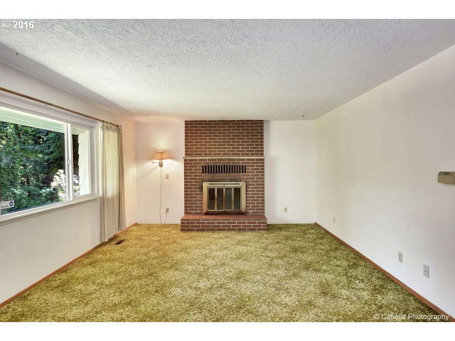 19428 Northwest Logie Trail Road Portland, OR 97231 - Photo 3 of 20 view of an empty room with a fireplace and a window