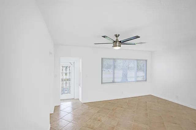 an empty room with windows and fan