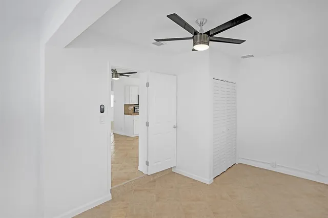 an empty room with closet and a ceiling fan