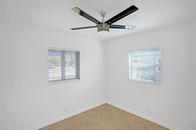an empty room with a ceiling fan and windows