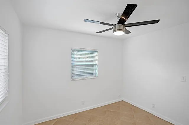 an empty room with a window and a fan
