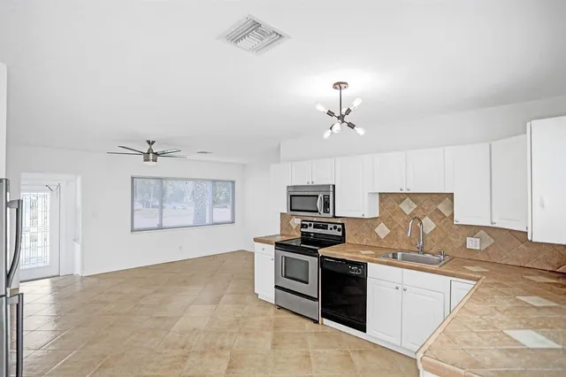 a kitchen with kitchen island granite countertop a stove top oven a sink a counter space and cabinets