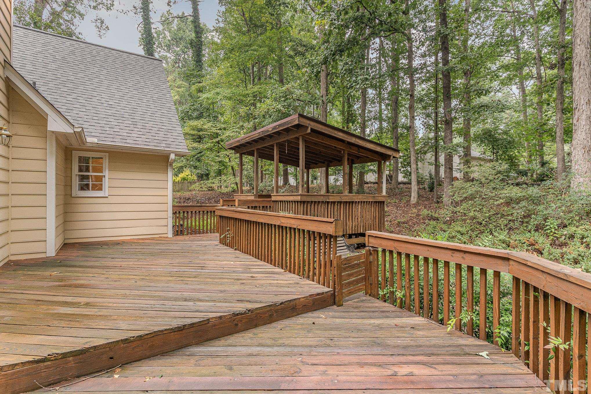 4909 Springwood Drive Raleigh, NC 27613 - Photo 49 of 59 a view of a wooden deck and a yard with trees
