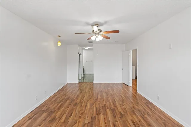 a view of a room with wooden floor a ceiling fan and closet
