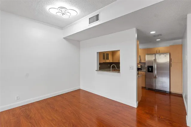 an empty room with wooden floor and a kitchen