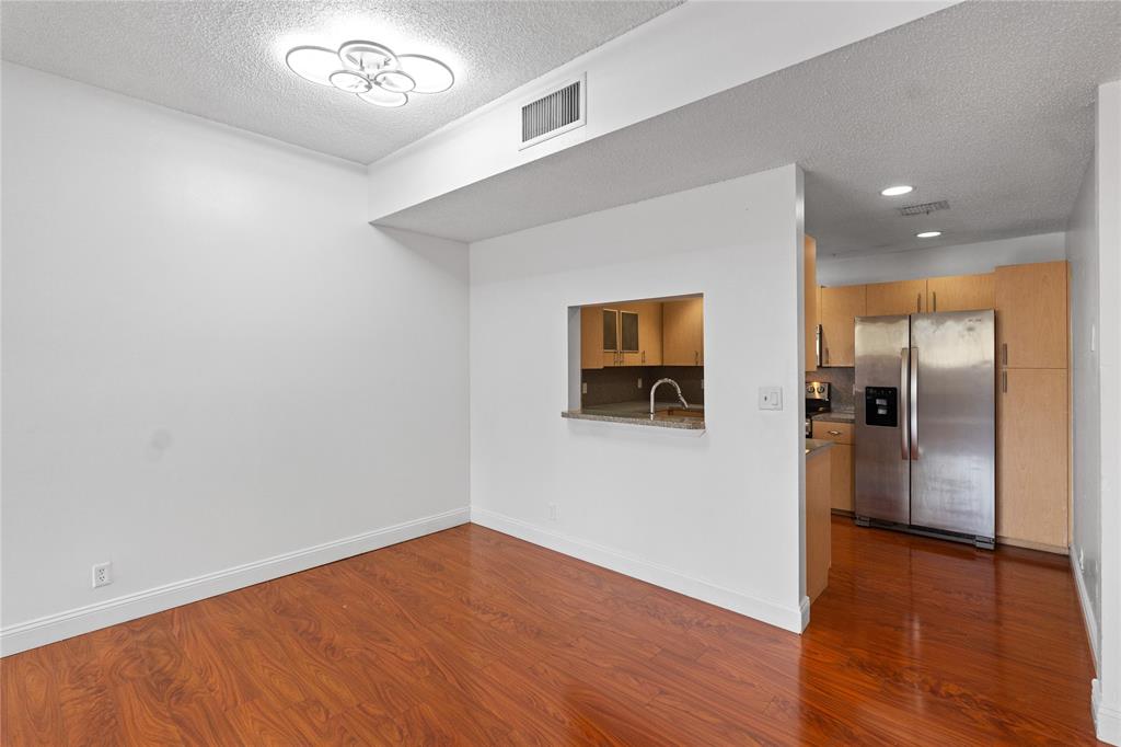 9580 Southwest 2nd Ct., Unit 9580 Pembroke Pines, FL 33025 - Photo 4 of 33 an empty room with wooden floor and a kitchen