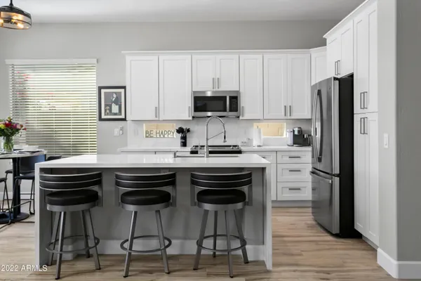 a kitchen with stainless steel appliances a sink a stove a refrigerator cabinets and dining table