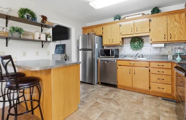 a kitchen with stainless steel appliances granite countertop a refrigerator a stove top oven a sink and dishwasher