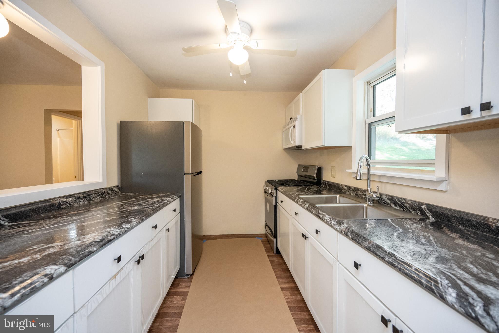 63 Wallman Road Oakland, MD 21550 - Photo 27 of 60 a kitchen with granite countertop a sink stove and refrigerator