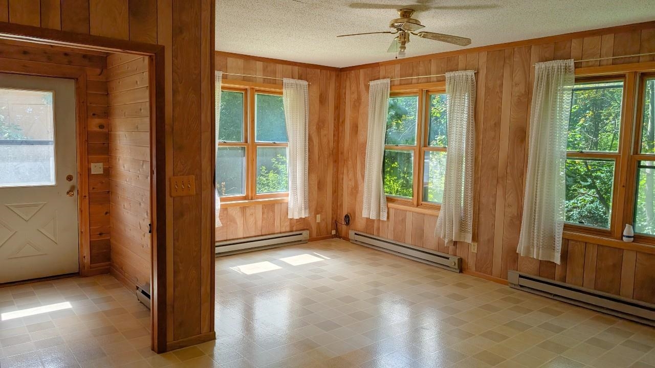 8159 Ludlow Road Cook, MN 55723 - Photo 12 of 32 Doorway to outside featuring wooden walls, healthy amount of natural light, tile patterned floors, baseboard heating, and ceiling fan