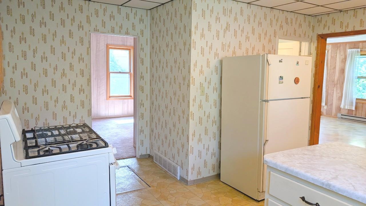 8159 Ludlow Road Cook, MN 55723 - Photo 16 of 32 Kitchen featuring white appliances, a paneled ceiling, light countertops, wallpapered walls, and light flooring