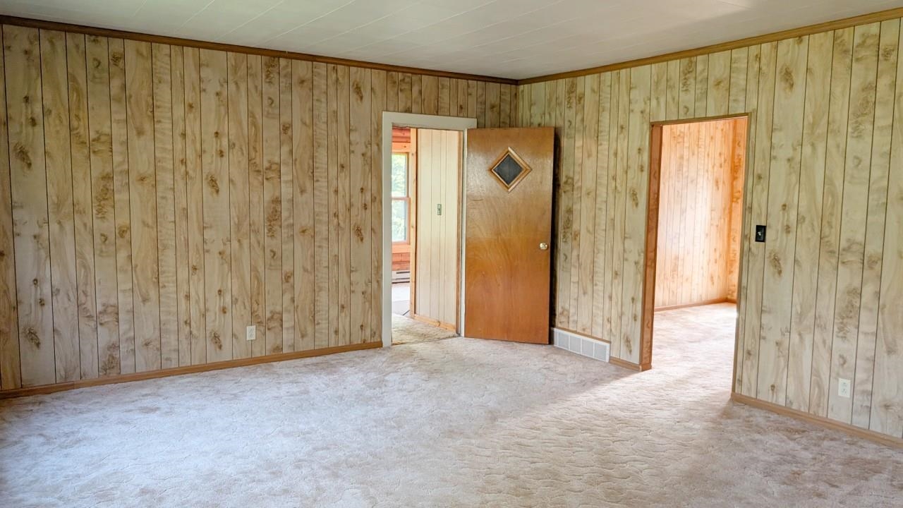 8159 Ludlow Road Cook, MN 55723 - Photo 17 of 32 Empty room featuring carpet floors, ornamental molding, and wooden walls