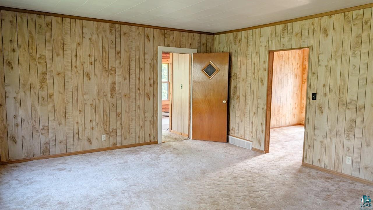 8159 Ludlow Road Cook, MN 55723 - Photo 17 of 32 Empty room featuring carpet floors, ornamental molding, and wooden walls