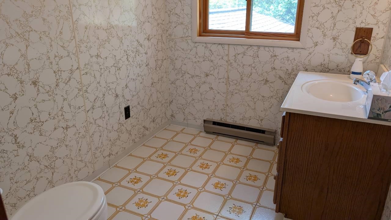 8159 Ludlow Road Cook, MN 55723 - Photo 21 of 32 Half bathroom with wallpapered walls, vanity, and a baseboard radiator