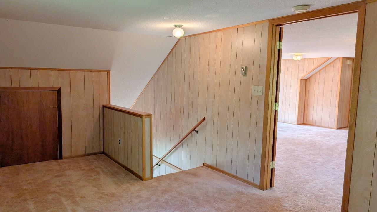 8159 Ludlow Road Cook, MN 55723 - Photo 22 of 32 Corridor featuring wood walls, an upstairs landing, carpet floors, and a textured ceiling