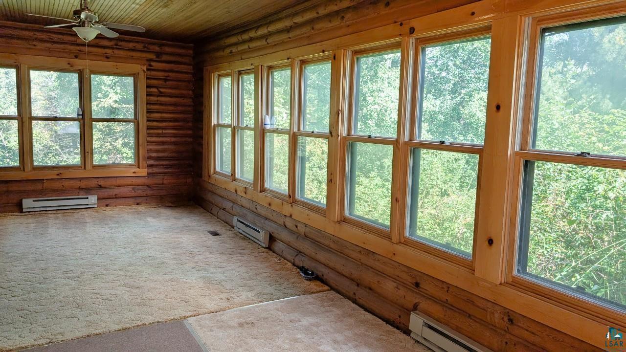 8159 Ludlow Road Cook, MN 55723 - Photo 9 of 32 Unfurnished sunroom featuring healthy amount of natural light, a baseboard radiator, wooden ceiling, and rustic walls