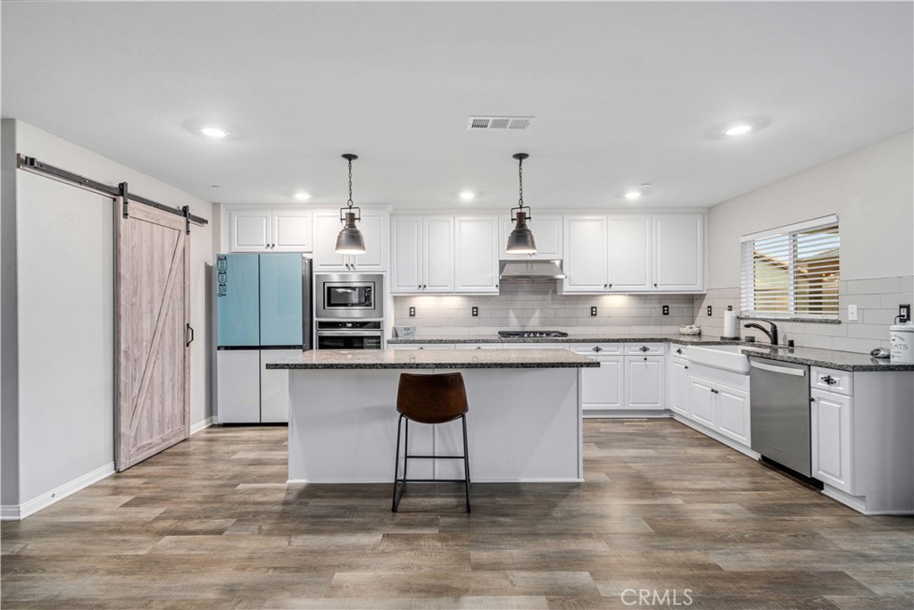 44451 63rd Street West Lancaster, CA 93536 - Photo 12 of 47 a kitchen with stainless steel appliances granite countertop a refrigerator a sink dishwasher a stove and white cabinets with wooden floor