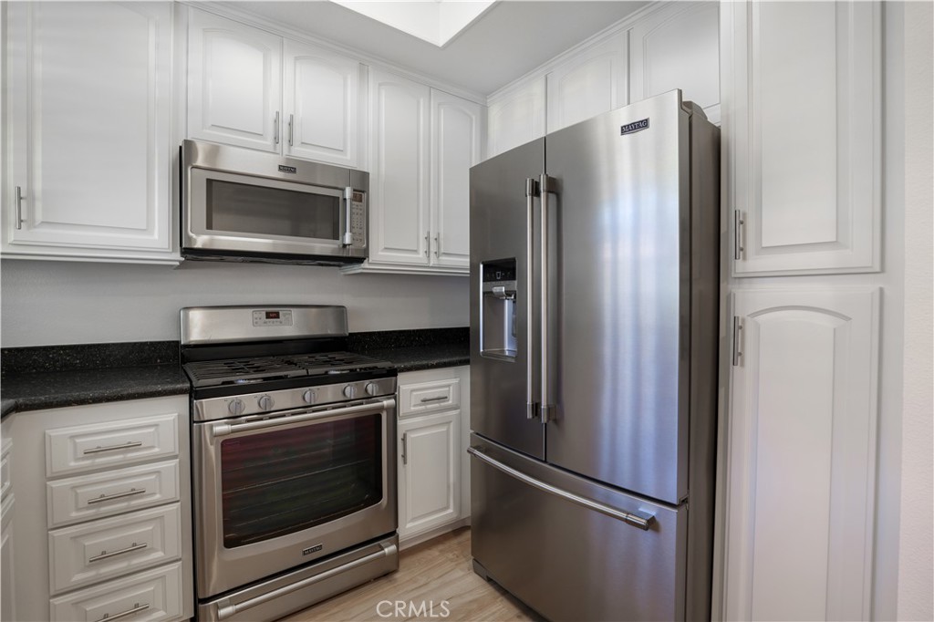 30902 Club House Drive, Unit 11J Laguna Niguel, CA 92677 - Photo 26 of 32 a kitchen with stainless steel appliances white cabinets white stove a microwave and a refrigerator