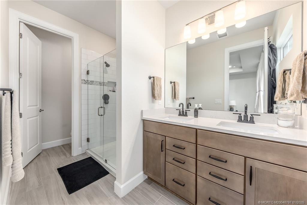 1865 Southeast Tarni Way Stuart, FL 34996 - Photo 12 of 23 a spacious bathroom with a double vanity sink a mirror and a shower