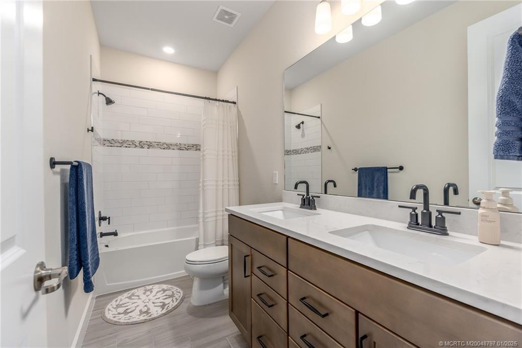 1865 Southeast Tarni Way Stuart, FL 34996 - Photo 16 of 23 a bathroom with a sink a toilet and a large mirror