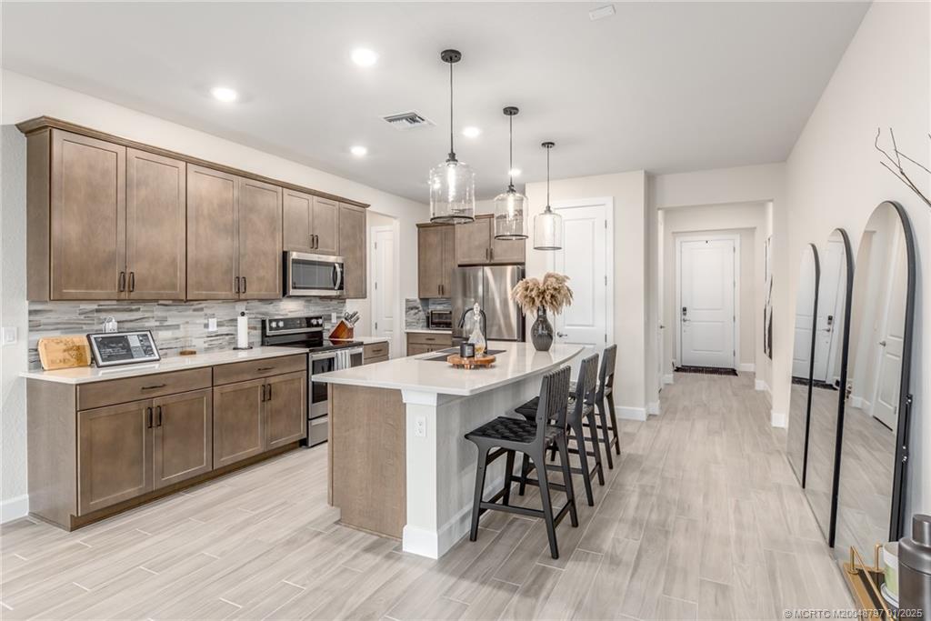 1865 Southeast Tarni Way Stuart, FL 34996 - Photo 4 of 23 a kitchen with stainless steel appliances kitchen island granite countertop a refrigerator a stove a sink dishwasher a dining table and chairs with wooden floor