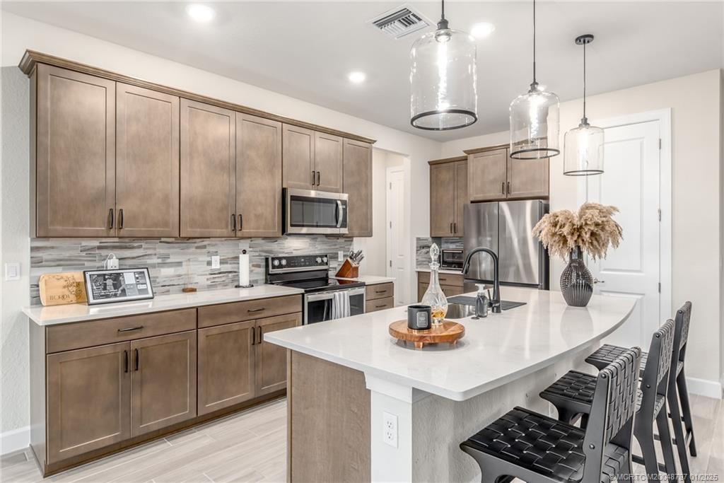 1865 Southeast Tarni Way Stuart, FL 34996 - Photo 5 of 23 a kitchen with a stove a sink a kitchen island with chairs and wooden cabinets