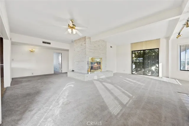 a view of a livingroom with wooden floor a ceiling fan and windows