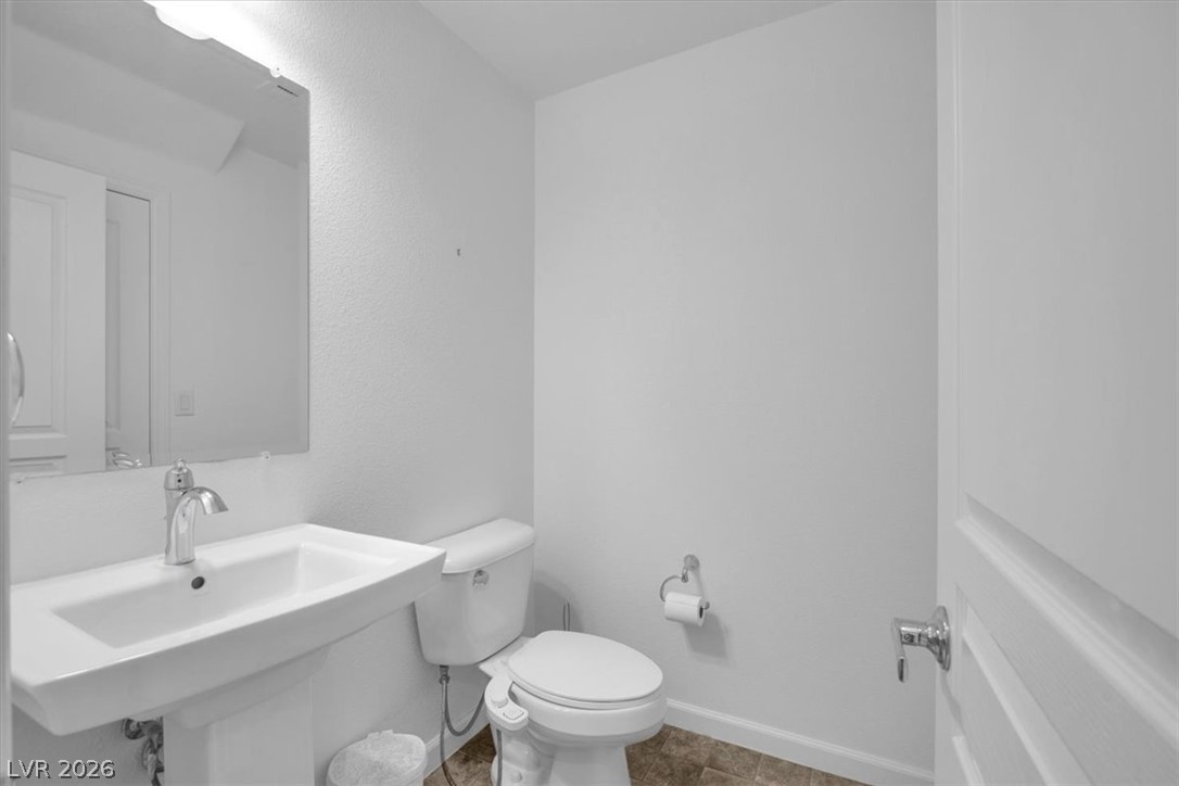 8046 Noble Ridge Street Las Vegas, NV 89139 - Photo 13 of 34 A pristine powder room featuring a sleek pedestal sink and contemporary toilet.