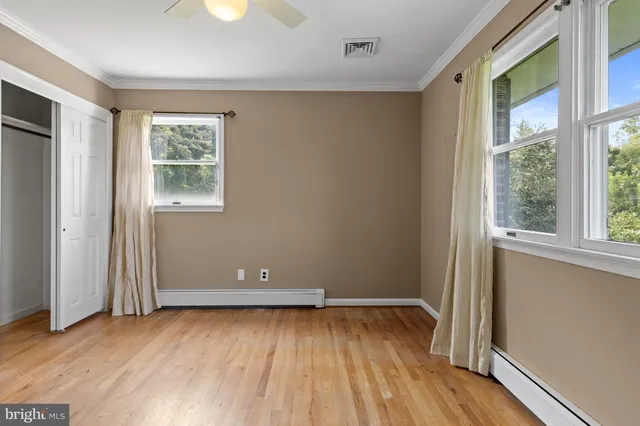 a view of an empty room with window and wooden floor