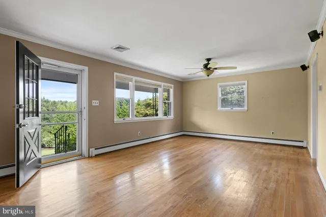 an empty room with wooden floor and windows