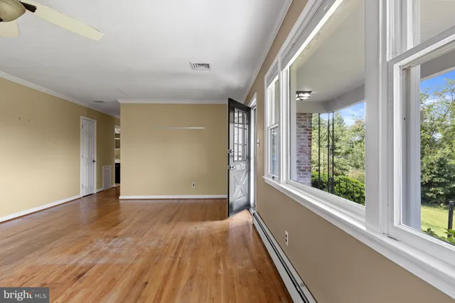 a view of an empty room with wooden floor and a window