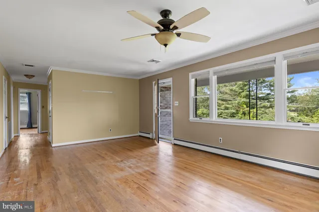 a view of an empty room with a window and wooden floor