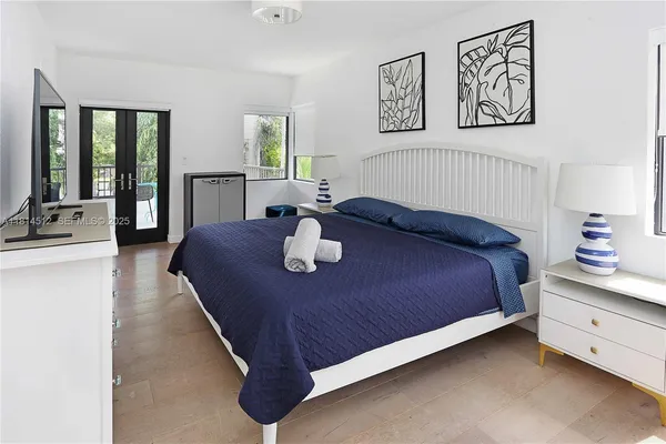 a bed sitting in a bedroom next to a window with a table and lamp
