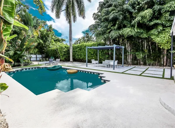 a view of a swimming pool with a yard and palm trees