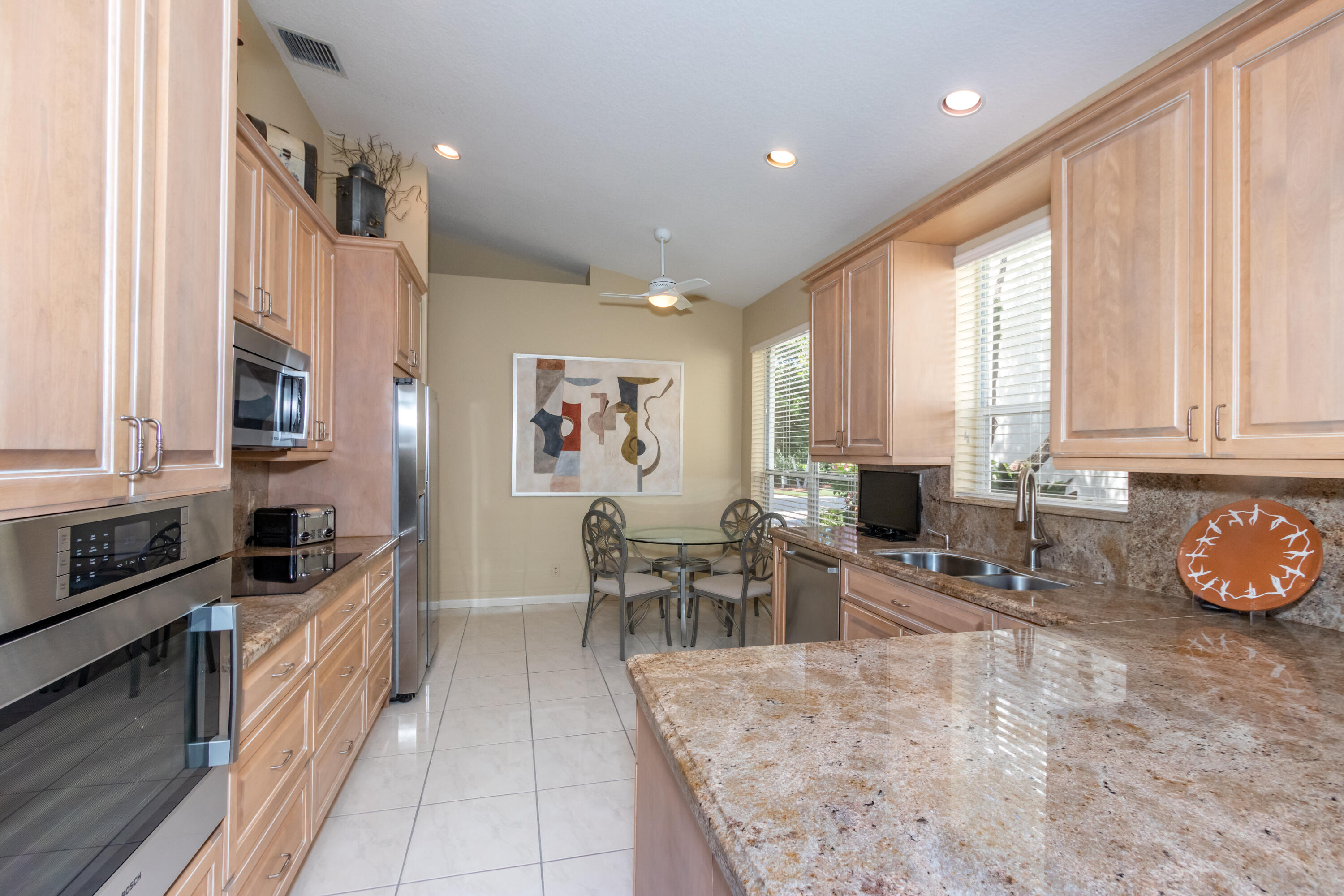 23402 Torre Circle Boca Raton, FL 33433 - Photo 14 of 44 a kitchen with granite countertop a stove a sink a dining table and chairs