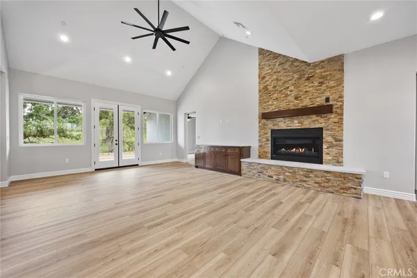 an empty room with windows fireplace and wooden floor