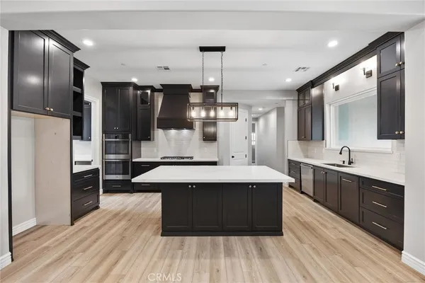 a large kitchen with stainless steel appliances a large counter top a sink a stove and refrigerator