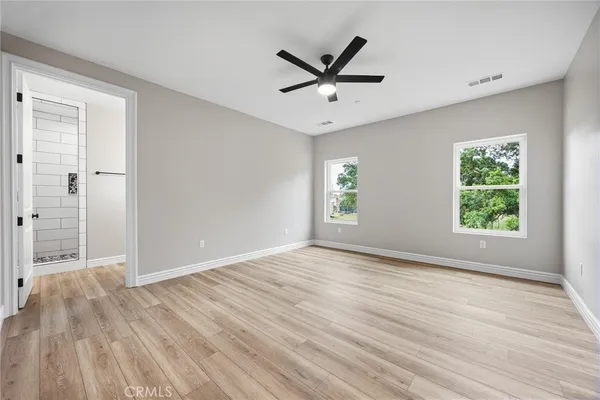 an empty room with wooden floor and a ceiling fan